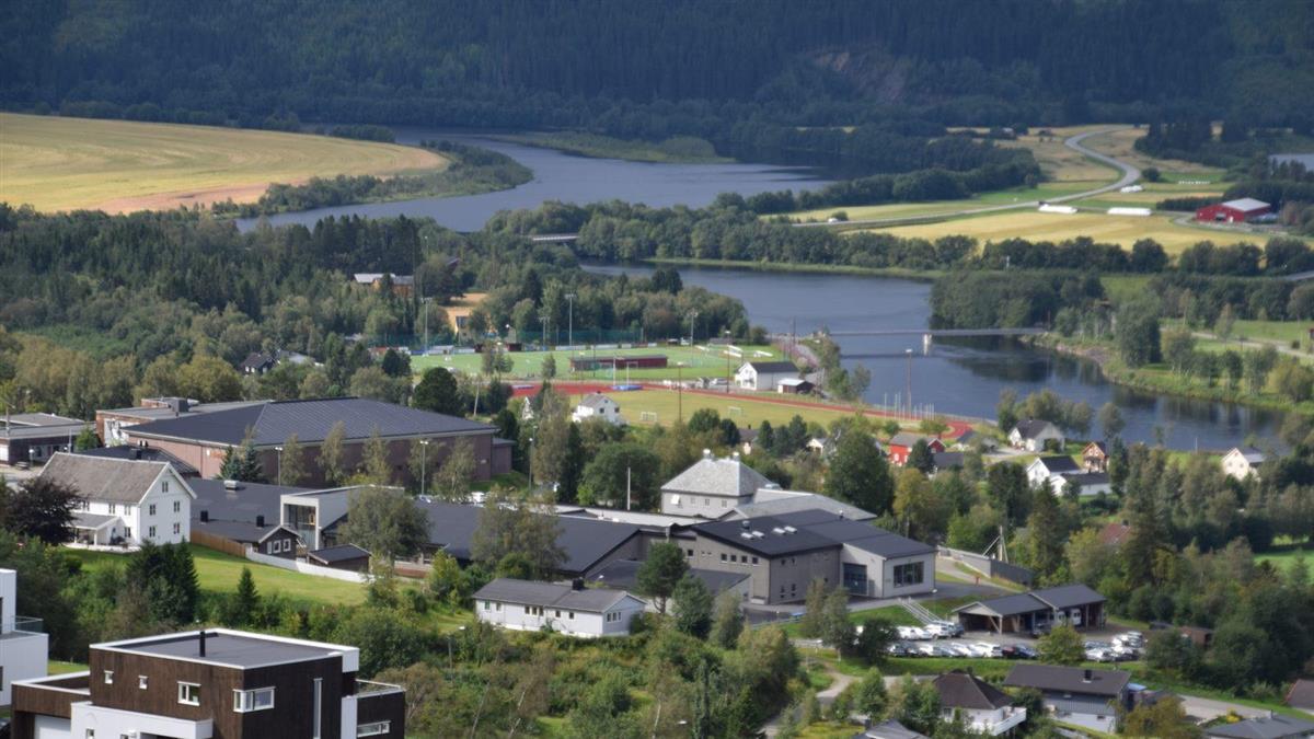 Boliger og skoleområdet i Selbu sentrum, med idrettsbanen og elva i bakgrunnen. - Klikk for stort bilde